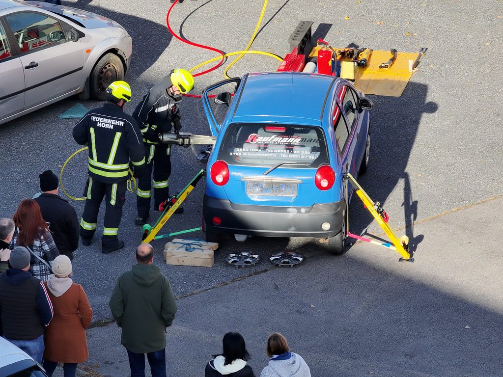 Feuerwehrmitglieder demonstrieren an einem blauen Pkw den Einsatz hydraulischer Rettungsgeräte bei einer technischen Hilfeleistung.