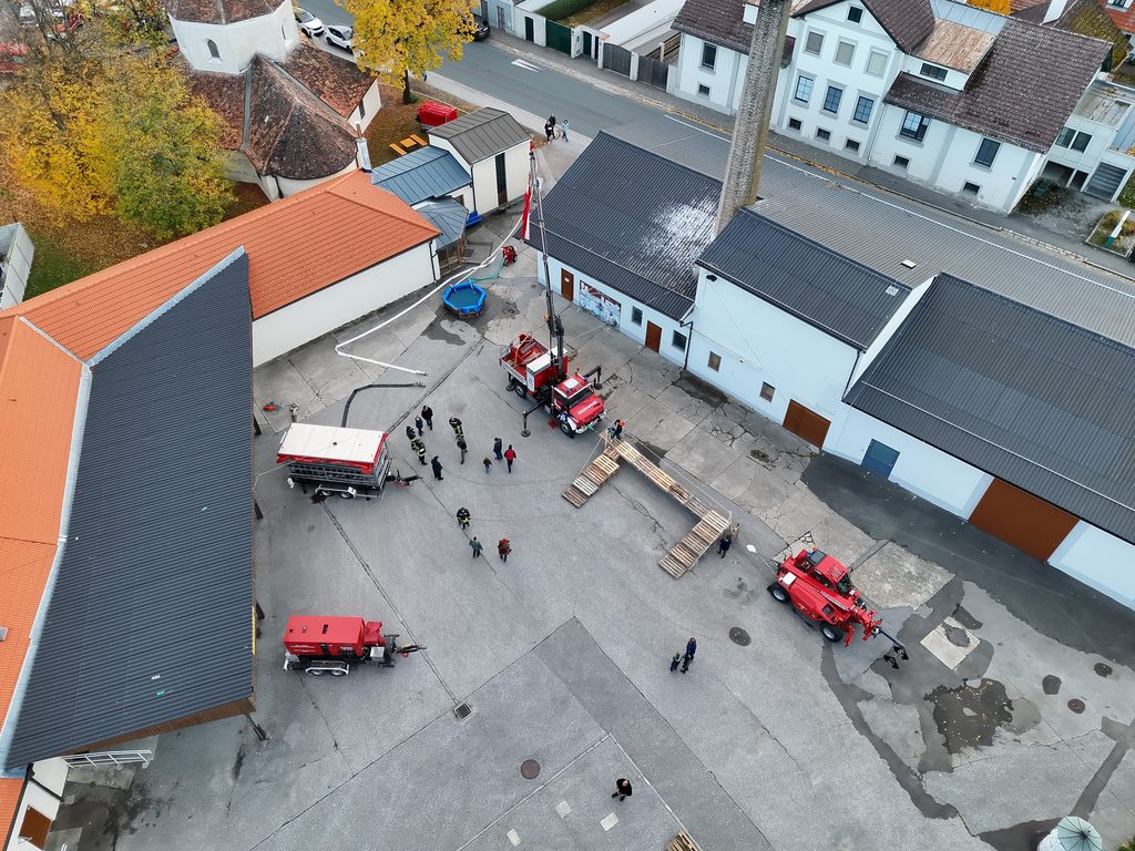 Luftaufnahme eines Innenhofs mit mehreren Feuerwehrfahrzeugen und aufgestellten Geräten bei einer Feuerwehrveranstaltung.