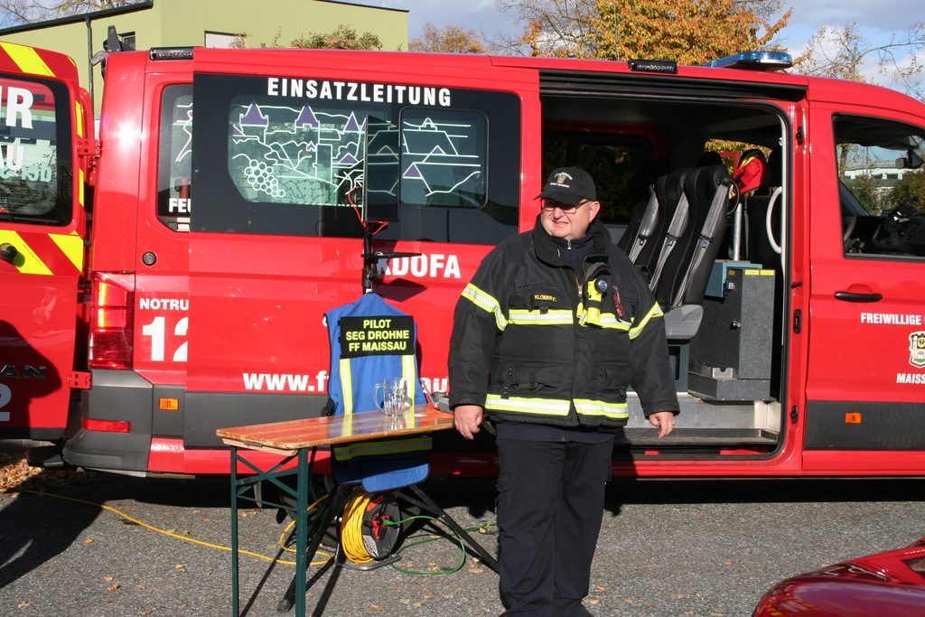 Ein Feuerwehrmitglied der Feuerwehr Maissau steht neben dem Einsatzfahrzeug der Drohnengruppe mit geöffneter Seitentür.